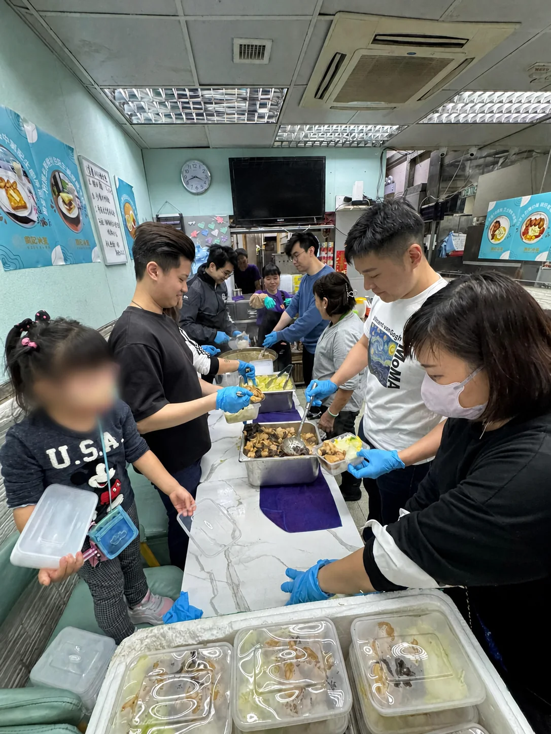 義工在餐桌旁分工包裝飯餐